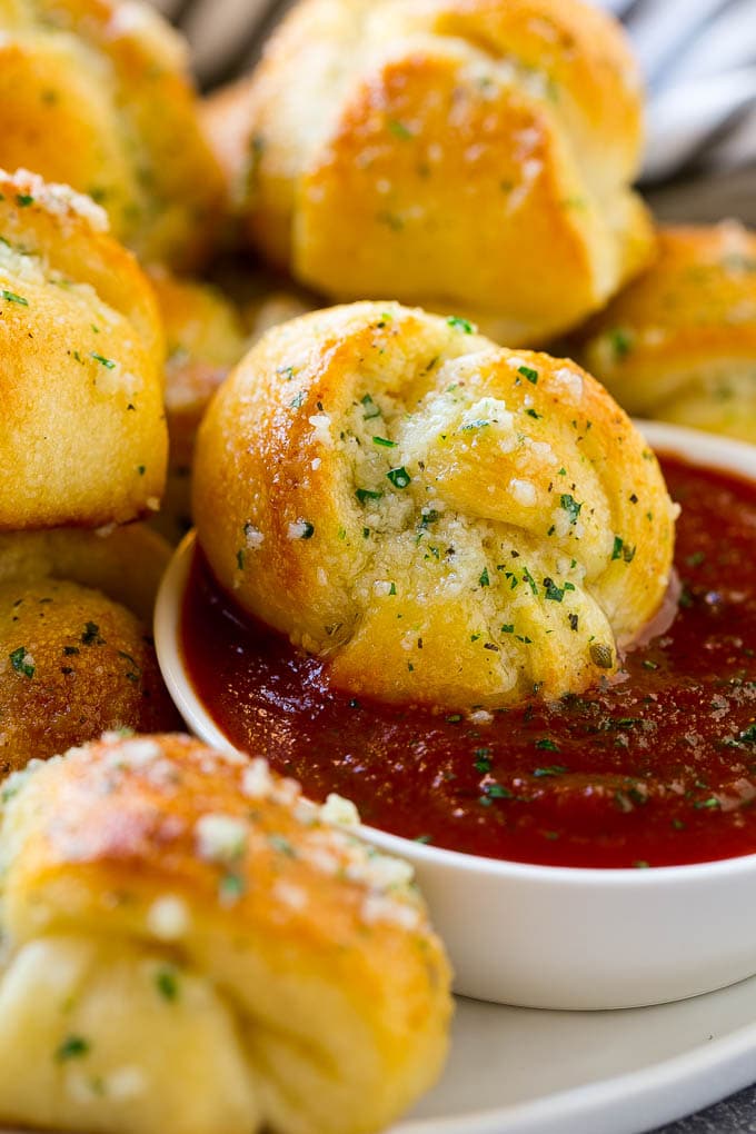 Garlic Knots Recipe | Garlic Rolls | Garlic Butter Rolls | Garlic Bread Recipe #garlic #garlicbread #garlicknots #breadsticks #sadud A garlic roll being dipped into marinara sauce for a delicious finishing touch.