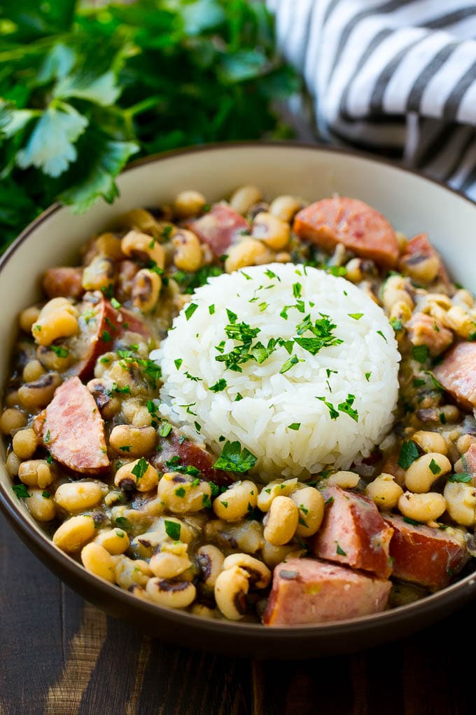 Slow Cooker Black Eyed Peas Recipe | Crock Pot Black Eyed Peas | Southern Black Eyed Peas | Black Eyed Peas with Ham | Black Eyed Peas with Sausage #blackeyedpeas #slowcooker #crockpot #sausage #newyears #dinner #sadud A bowl of slow cooker black eyed peas with a scoop of rice.