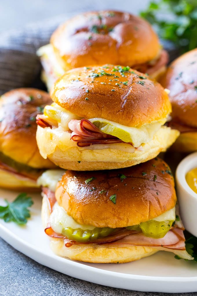 Cuban Sliders Recipe | Cuban Sandwich Recipe | Slider Sandwiches | Ham and Cheese Sliders #sliders #sandwiches #ham #cheese #appetizer #sadud A pile of cuban sliders filled with ham, cheese and pickles.