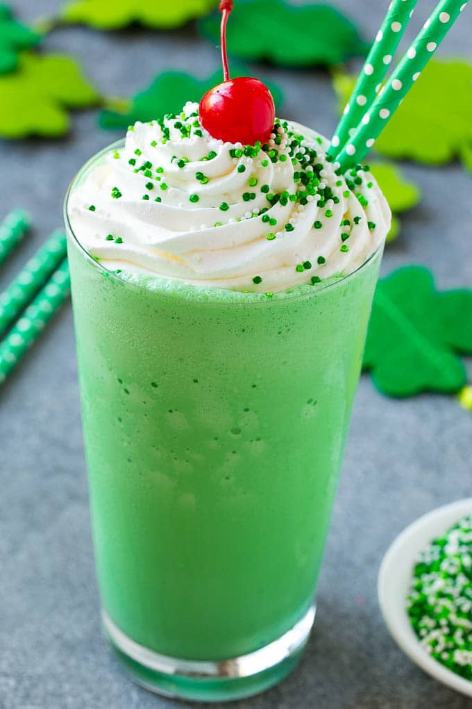 Shamrock Shake Recipe | McDonald's Shamrock Shake | Saint Patrick's Day Drink | Mint Milkshake #milkshake #stpatricksday #saintpatricksday #mint #sadud A glass of shamrock shake topped with whipped cream, sprinkles and a cherry.