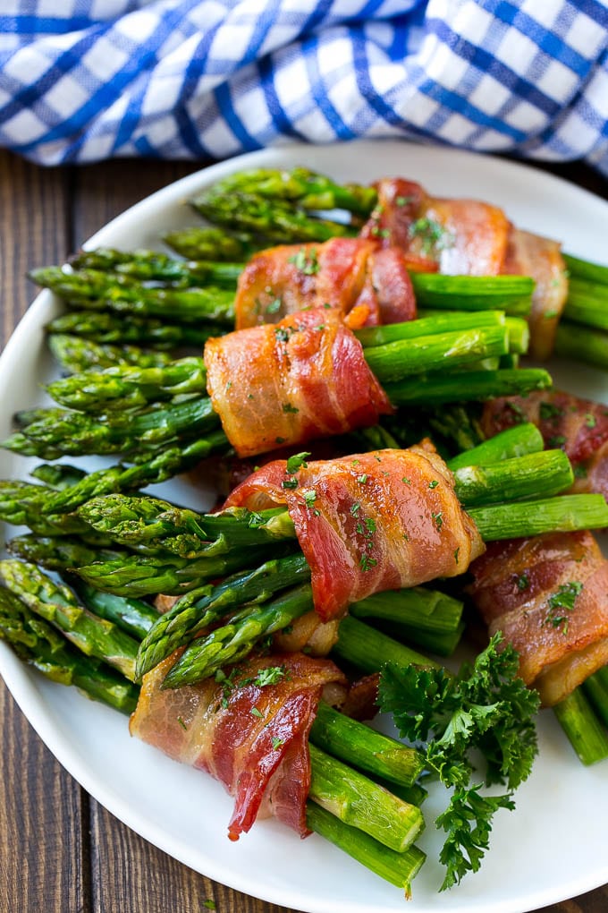 Bacon Wrapped Asparagus Recipe | Roasted Asparagus | Asparagus Side Dish #asparagus #bacon #sidedish #dinner #sadud A plate of bacon wrapped asparagus bundles garnished with parsley.