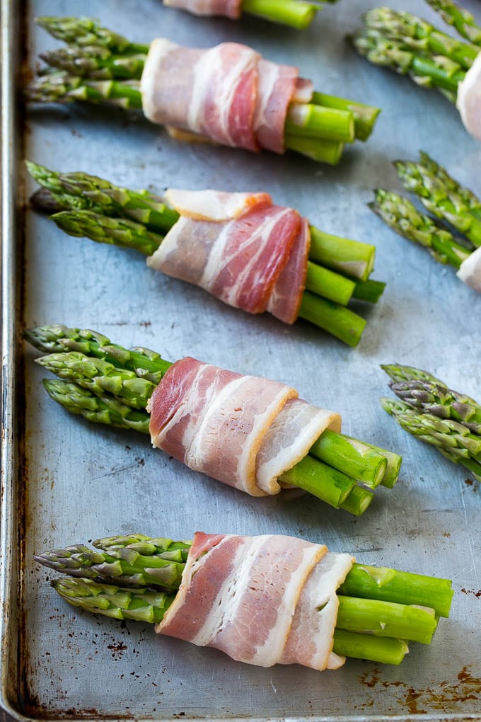 Bacon Wrapped Asparagus Recipe | Roasted Asparagus | Asparagus Side Dish #asparagus #bacon #sidedish #dinner #sadud Raw asparagus bundles on a sheet pan.