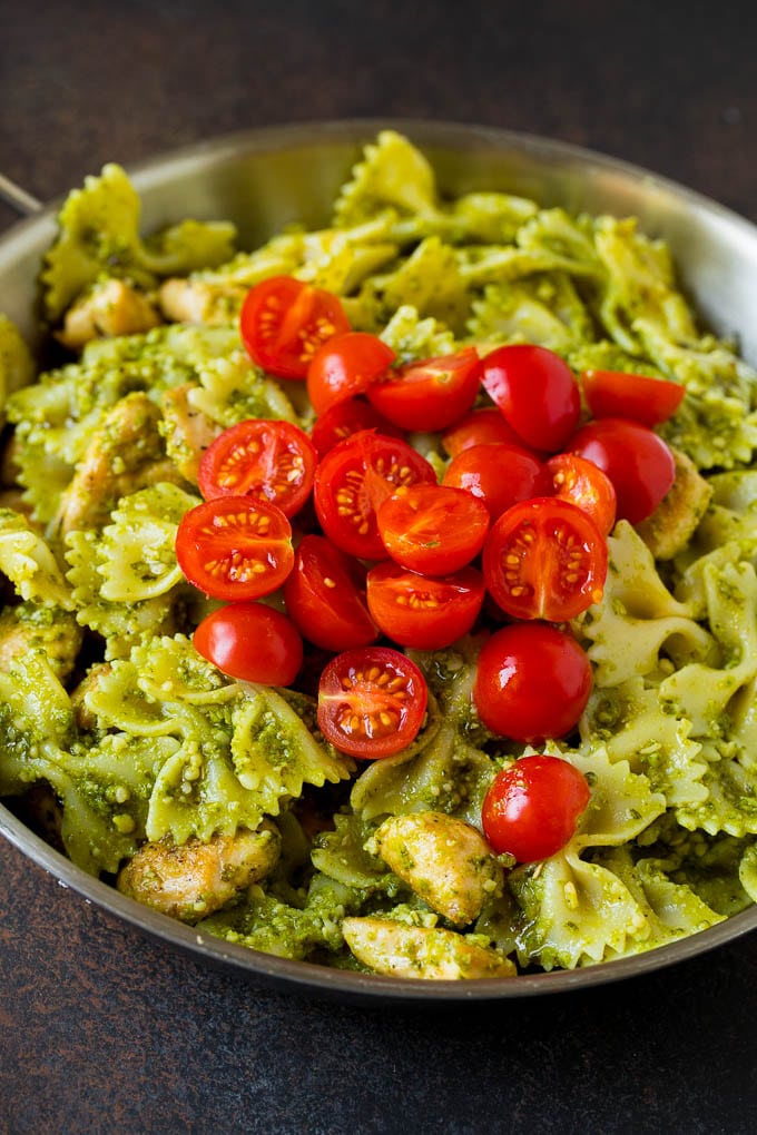 This chicken pesto pasta is sauteed chicken, farfalle pasta and cherry tomatoes, all tossed in basil pesto and finished off with parmesan cheese. Chicken and pasta topped with cherry tomatoes.
