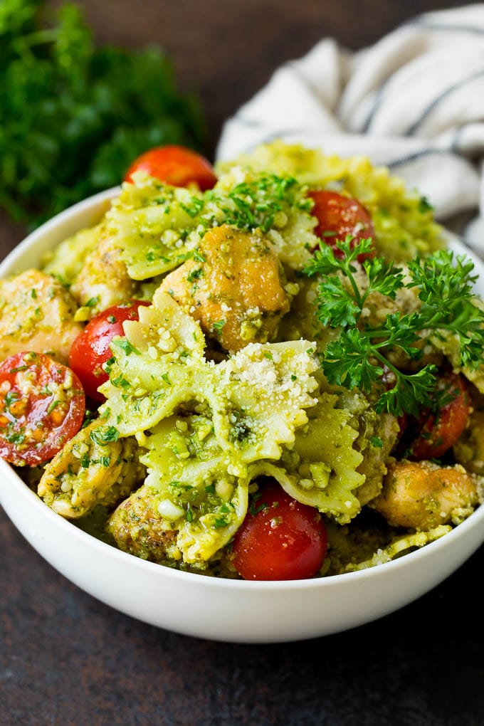 This chicken pesto pasta is sauteed chicken, farfalle pasta and cherry tomatoes, all tossed in basil pesto and finished off with parmesan cheese. A bowl of chicken pesto pasta garnished with parsley.