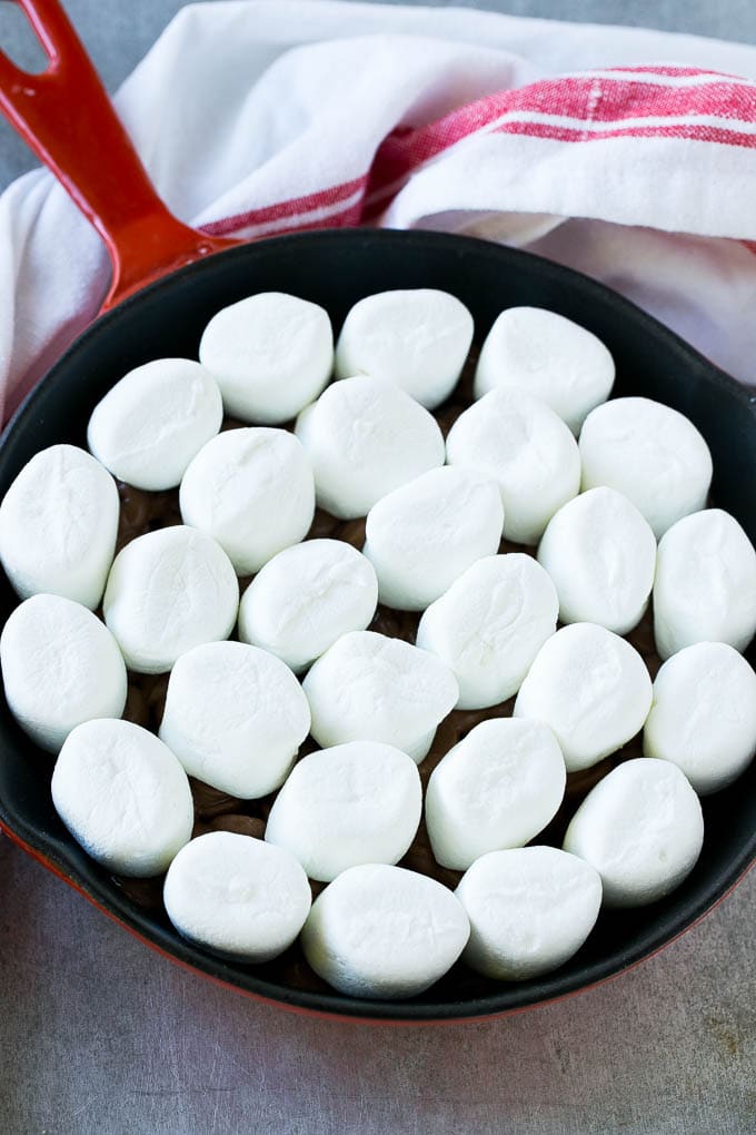 S'mores Dip Recipe | S'mores Skillet | Baked S'mores #smores #dip #chocolate #marshmallow #dessert #sadud A pan of chocolate chips topped with whole marshmallows.