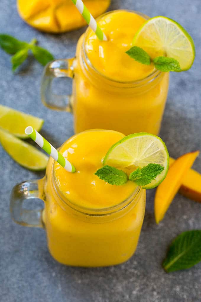 Mango Smoothie Recipe | Mango Recipe | Healthy Smoothie #mango #smoothie #drink #sadud Two jars full of mango smoothie, garnished with lime slices and fresh mint.