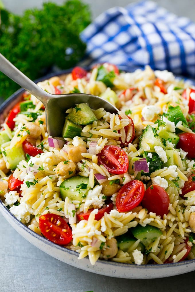 Orzo Salad Recipe | Orzo Pasta Salad | Greek Orzo Salad | Mediterranean Orzo Salad #pastasalad #orzo #greekfood #salad #sadud Orzo pasta salad with a serving spoon in the bowl.