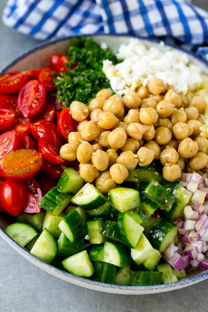 Orzo Salad Recipe | Orzo Pasta Salad | Greek Orzo Salad | Mediterranean Orzo Salad #pastasalad #orzo #greekfood #salad #sadud A bowl of orzo pasta, tomatoes, cucumbers, red onions, chickpeas and feta cheese topped with dressing.
