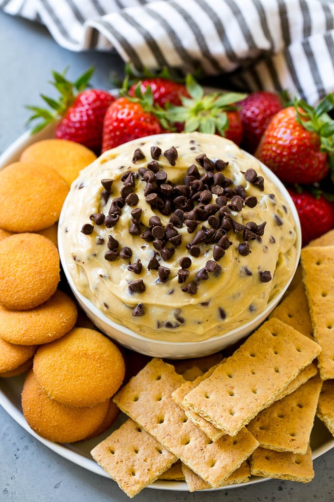 Cookie Dough Dip Recipe | Edible Cookie Dough | Chocolate Chip Cookie Dip #cookies #dip #cookiedough #dessert #snack #sadud A bowl of cookie dough dip topped with chocolate chips and served with cookies and fruit for dipping.