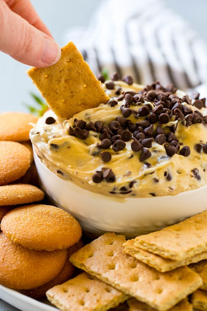 Cookie Dough Dip Recipe | Edible Cookie Dough | Chocolate Chip Cookie Dip #cookies #dip #cookiedough #dessert #snack #sadud A graham cracker dipping into a bowl of cookie dough dip.
