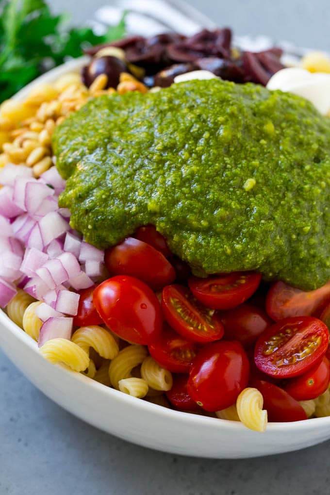 Pesto Pasta Salad | Italian Pasta Salad | Easy Pasta Salad #pasta #salad #pesto #olives #tomatoes #sadud Vegetables and corkscrew pasta topped with fresh pesto.