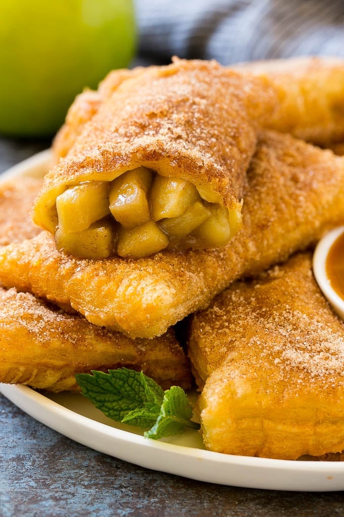 Fried Apple Pies Recipe | McDonald's Copycat Recipe | Apple Pie | Apple Hand Pies #pie #apples #applepie #dessert #snack #sadud Fried apple pies on a plate served with caramel sauce and topped with cinnamon sugar.
