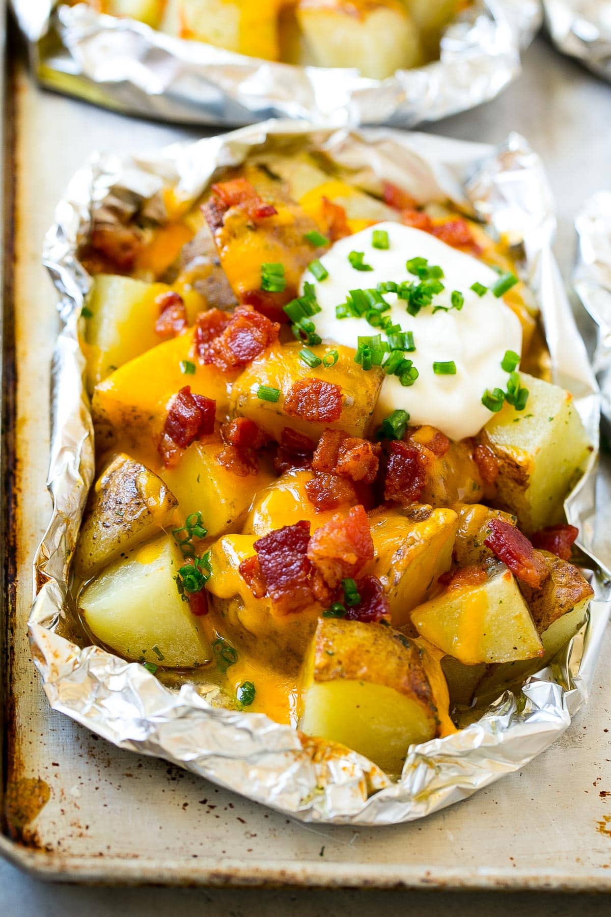 Grilled potatoes in foil with cheese, bacon and sour cream.