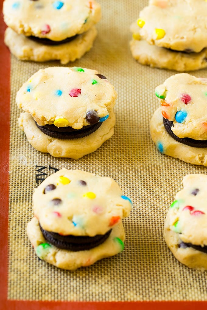 Oreo Stuffed Cookies Recipe | M&M's cookies | Stuffed Cookies #cookies #chocolate #oreos #dessert #baking #sadud Cookie dough sandwiched around Oreos on a baking sheet.