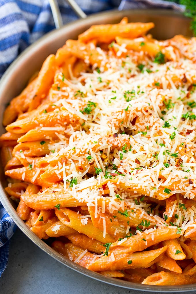 This Penne alla Vodka is tender penne pasta tossed in a rich and delicious tomato, vodka and cream sauce. Add a sprinkling of parmesan cheese and you'll have a restaurant quality meal in the comfort of your own home. A skillet of penne alla vodka topped with shredded parmesan cheese.