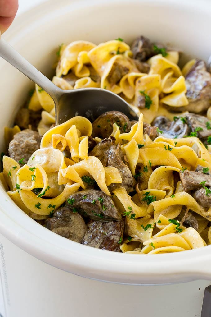 Slow Cooker Beef Stroganoff Recipe | Crock Pot Beef Stroganoff | Beef Recipe #slowcooker #crockpot #beef #mushrooms #pasta #dinner #sadud A crock pot of beef stroganoff with a serving spoon in it.