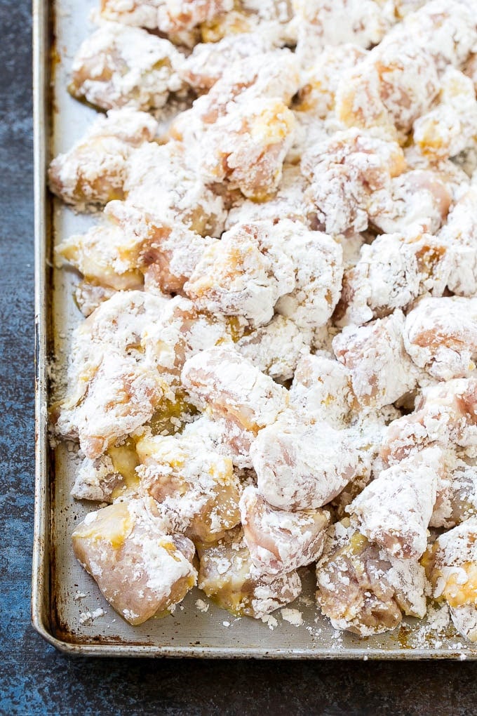Sweet and Sour Chicken Recipe | Chinese Food Copycat Recipe | Chicken with Pineapple #chicken #chinesefood #pineapple #stirfry #takeout #dinner #sadud Chicken pieces coated in egg and flour on a baking sheet.
