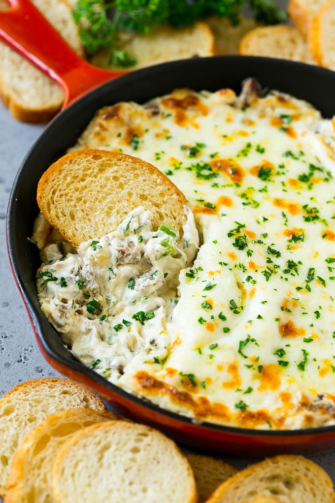 Philly Cheesesteak Dip Recipe | Cheesy Dip | Baked Cheese Dip #steak #dip #appetizer #cheese #sadud Philly cheesesteak dip with a baguette piece scooping some dip out.