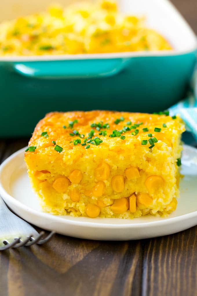 Corn Pudding Recipe | Corn Casserole | Corn Side Dish #corn #pudding #casserole #sidedish #thanksgiving #dinner #sadud A serving of corn pudding on a plate, garnished with chives.