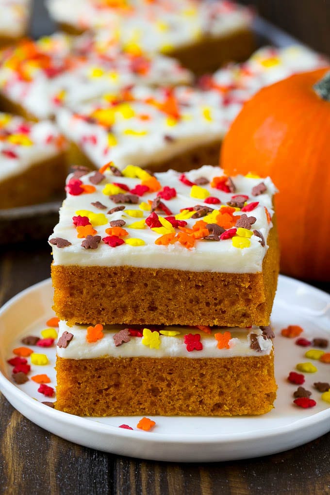 Pumpkin Bars Recipe | Pumpkin Cake | Pumpkin Dessert #pumpkin #fall #dessert #sadud #thanksgiving A stack of pumpkin bars topped with frosting and sprinkles.