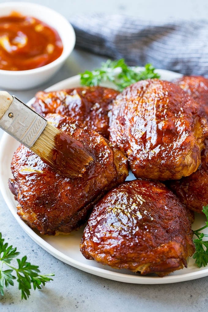 Smoked Chicken Thighs Recipe | Barbecue Chicken Thighs | Easy Chicken Thighs #chicken #barbecue #smoker #dinner #sadud A plate of smoked chicken thighs being basted with barbecue sauce.
