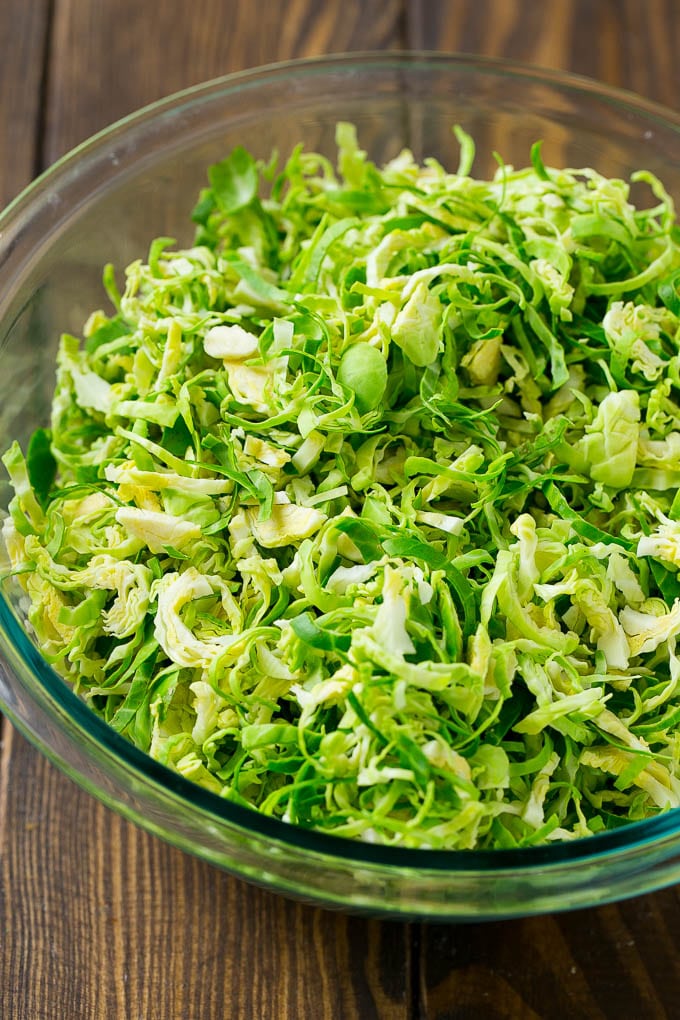 Brussels Sprout Salad Recipe | Shredded Brussels Sprouts Salad | Fall Salad #salad #brusselssprouts #bacon #thanksgiving #pomegranate #apple #dinner #sadud Shredded sprouts in a glass bowl.