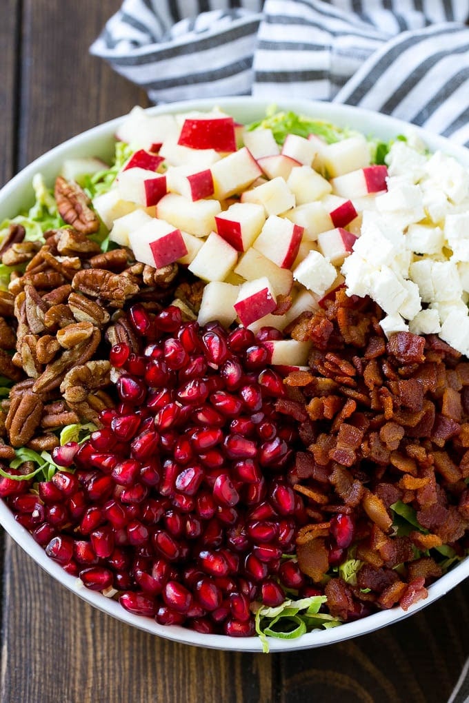 Brussels Sprout Salad Recipe | Shredded Brussels Sprouts Salad | Fall Salad #salad #brusselssprouts #bacon #thanksgiving #pomegranate #apple #dinner #sadud Shredded brussels sprouts topped with pomegranate seeds, bacon, feta cheese and apples.