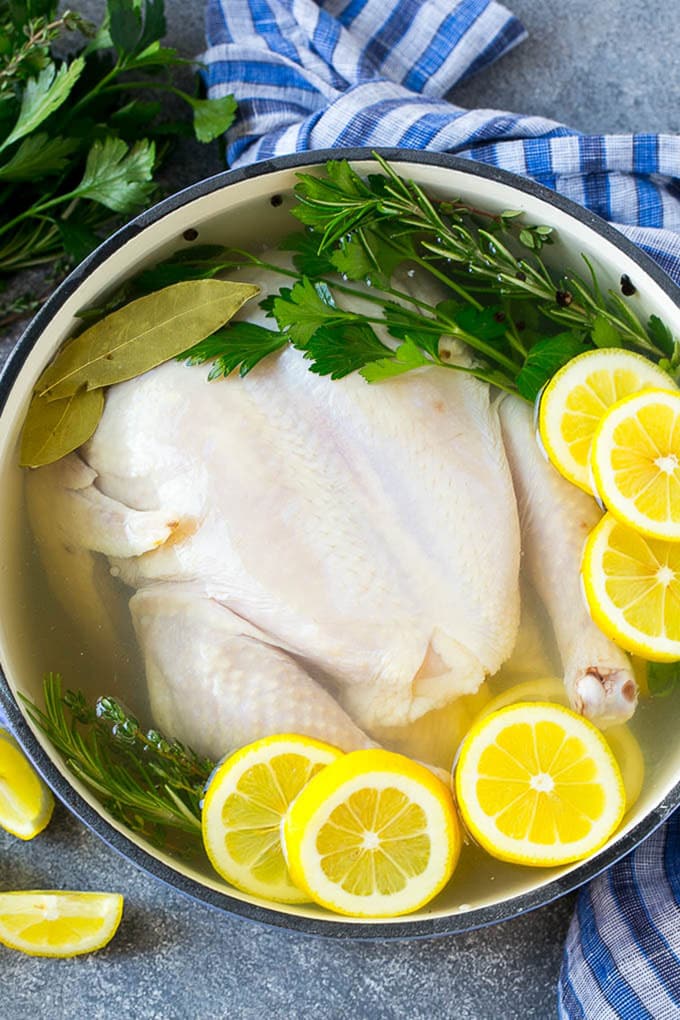 This chicken brine recipe is made with lemons, honey, fresh herbs and spices, and produces a juicy tender chicken every time! A foolproof way for succulent and flavorful roasted, smoked or fried chicken. Chicken brine in a pot with a whole chicken, lemons, herbs and spices.