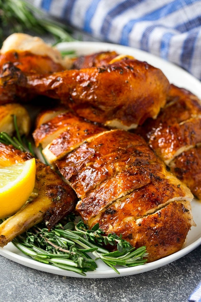This chicken brine recipe is made with lemons, honey, fresh herbs and spices, and produces a juicy tender chicken every time! A foolproof way for succulent and flavorful roasted, smoked or fried chicken. Sliced chicken garnished with fresh herbs.