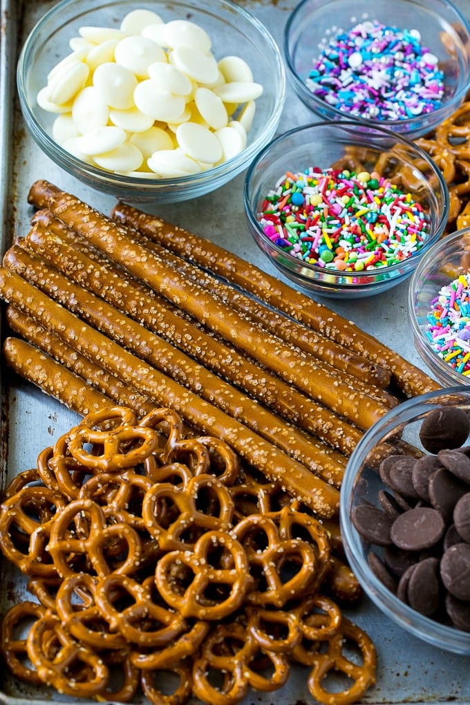 Chocolate Covered Pretzels Recipe | Sprinkle Pretzels | No Bake Dessert #pretzels #chocolate #christmas #sprinkles #candy #sadud Ingredients including candy melts and sprinkles on a sheet pan.