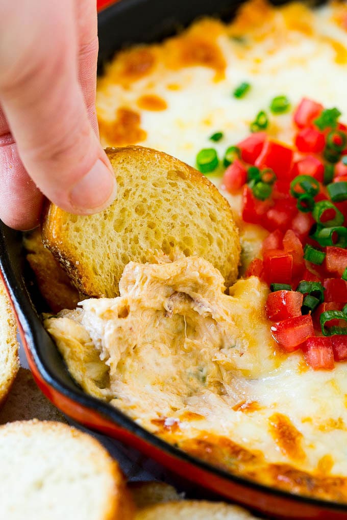 Crab Dip Recipe | Hot Crab Dip | Seafood Dip #dip #crab #seafood #appetizer #sadud #cheese A hand scooping out some crap dip with a crostini toast.