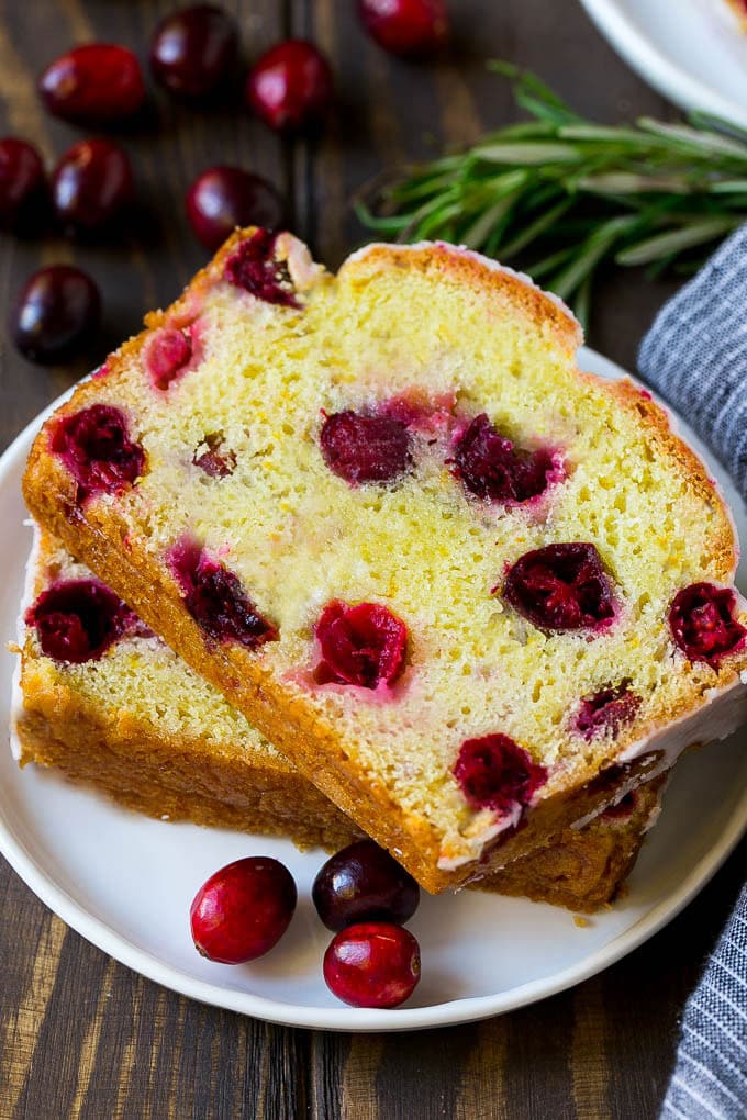 Cranberry Bread Recipe | Cranberry Loaf | Cranberry Orange Bread #cranberry #bread #baking #dessert #fall #sadud A plate with two slices of cranberry bread and fresh cranberries for garnish.