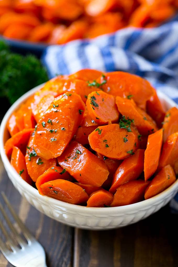 Glazed Carrots Recipe | Brown Sugar Carrots | Carrot Side Dish #carrots #brownsugar #sidedish #glutenfree #thanksgiving #fall #dinner #sadud A bowl of glazed carrots topped with parsley.