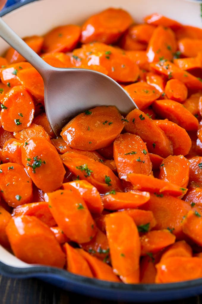 Glazed Carrots Recipe | Brown Sugar Carrots | Carrot Side Dish #carrots #brownsugar #sidedish #glutenfree #thanksgiving #fall #dinner #sadud Glazed carrots in a skillet with a serving spoon.