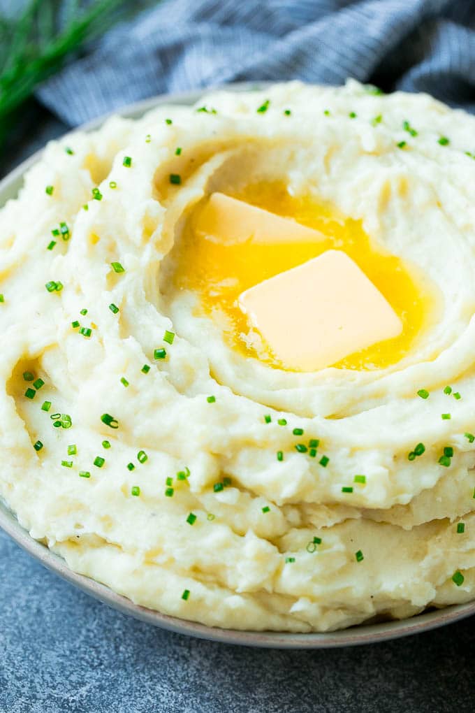 Instant Pot Mashed Potatoes Recipe | Pressure Cooker Mashed Potatoes | Easy Mashed Potatoes #potatoes #sidedish #instantpot #thanksgiving #dinner #sadud A bowl of fluffy Instant Pot mashed potatoes topped with pats of butter and sliced chives.