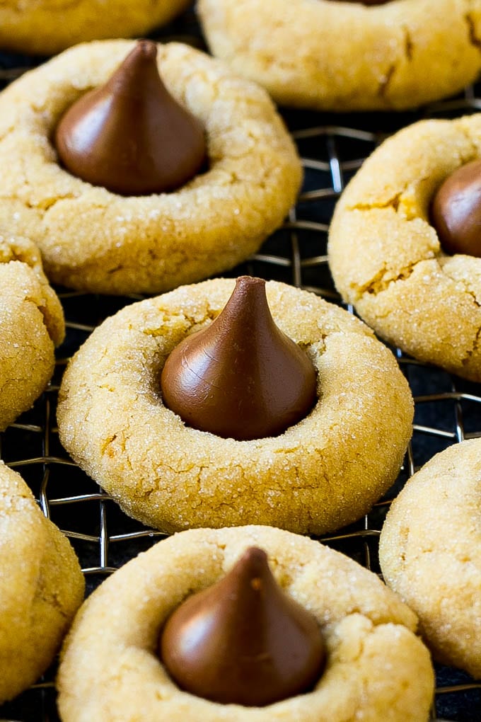 Peanut Butter Blossoms Recipe | Hershey Kiss Cookies | Chocolate Peanut Butter Cookies #cookies #peanutbutter #chocolate #dessert #baking #christmas #christmascookies #sadud Peanut butter blossom cookies on a cooling rack.