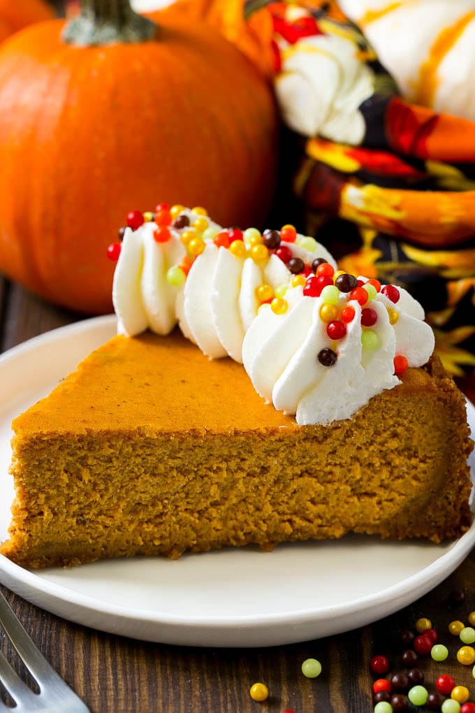 Pumpkin Cheesecake Recipe | Pumpkin Pie Cheesecake | Pumpkin Dessert #pumpkin #thanksgiving #dessert #cheesecake #fall #sadud A slice of pumpkin cheesecake on a graham cracker crust, topped with whipped cream and sprinkles.