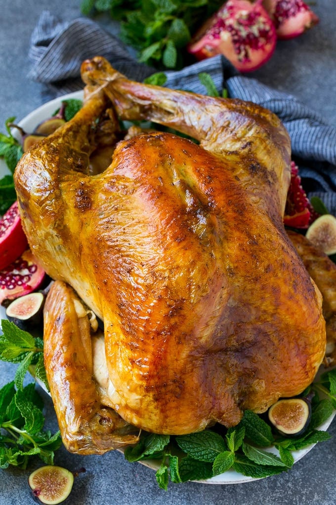 Roast Turkey Recipe | Thanksgiving Turkey | Holiday Turkey | Baked Turkey #turkey #thanksgiving #christmas #dinner #glutenfree #sadud A Thanksgiving roast turkey on a serving platter garnished with herbs, pomegranate and figs.