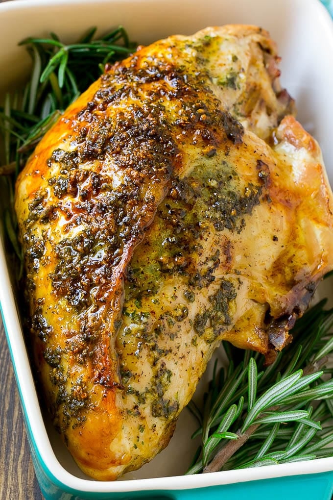 This roasted turkey breast is coated in a savory garlic and herb butter, then baked to golden brown perfection. Garlic and herb roasted turkey breast in a baking dish with a rosemary garnish.