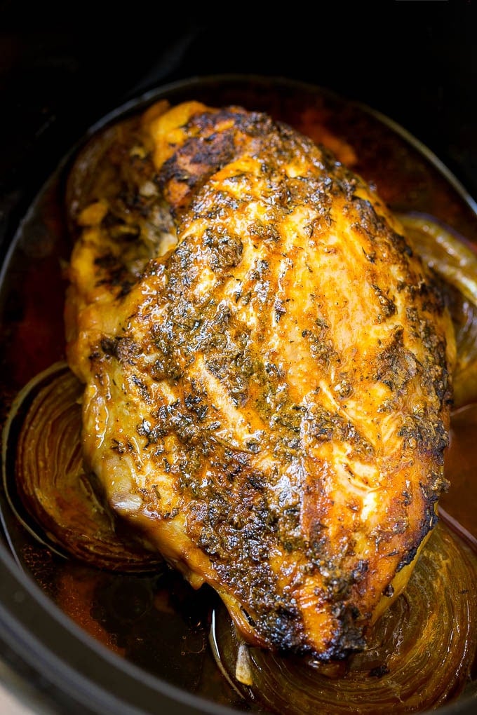 This slow cooker turkey breast is coated in a seasoned herb butter, then placed in the crock pot to cook to tender perfection. It's the perfect way to free up oven space for your big holiday meal. Cooked meat inside a crock pot.