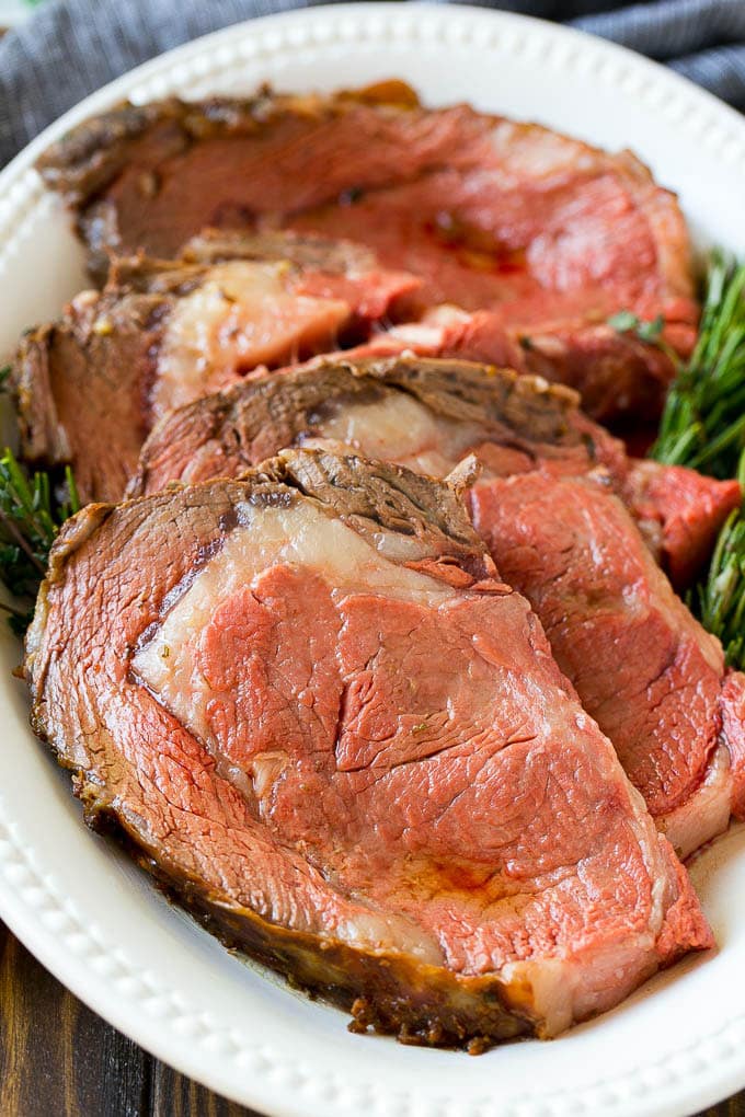 Smoked Prime Rib Recipe | Easy Prime Rib | Smoked Beef | Holiday Prime Rib #primerib #beef #smoker #dinner #sadud #christmas #thanksgiving #lowcarb #keto Slices of beef garnished with fresh herbs.