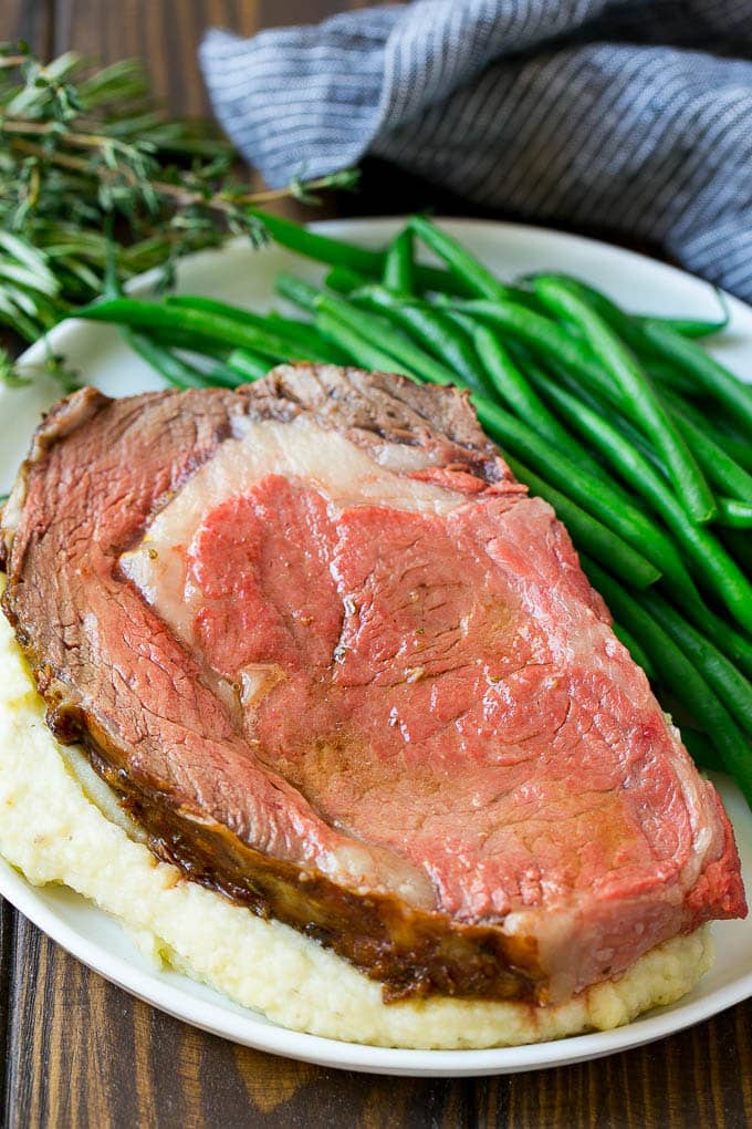 Smoked Prime Rib Recipe | Easy Prime Rib | Smoked Beef | Holiday Prime Rib #primerib #beef #smoker #dinner #sadud #christmas #thanksgiving #lowcarb #keto A slice of prime rib over mashed potatoes with green beans on the side.