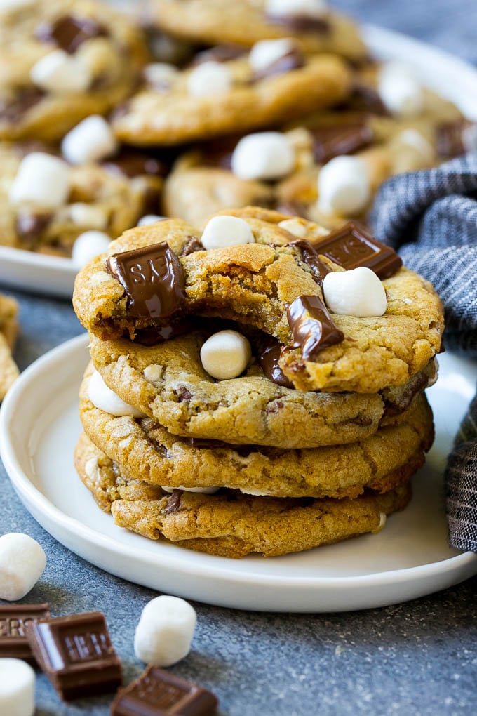 S'mores Cookies Recipe | Marshmallow Cookies #smores #marshmallow #chocolate #cookies #dessert #sadud A stack of S'mores cookies with a bite taken out of one.