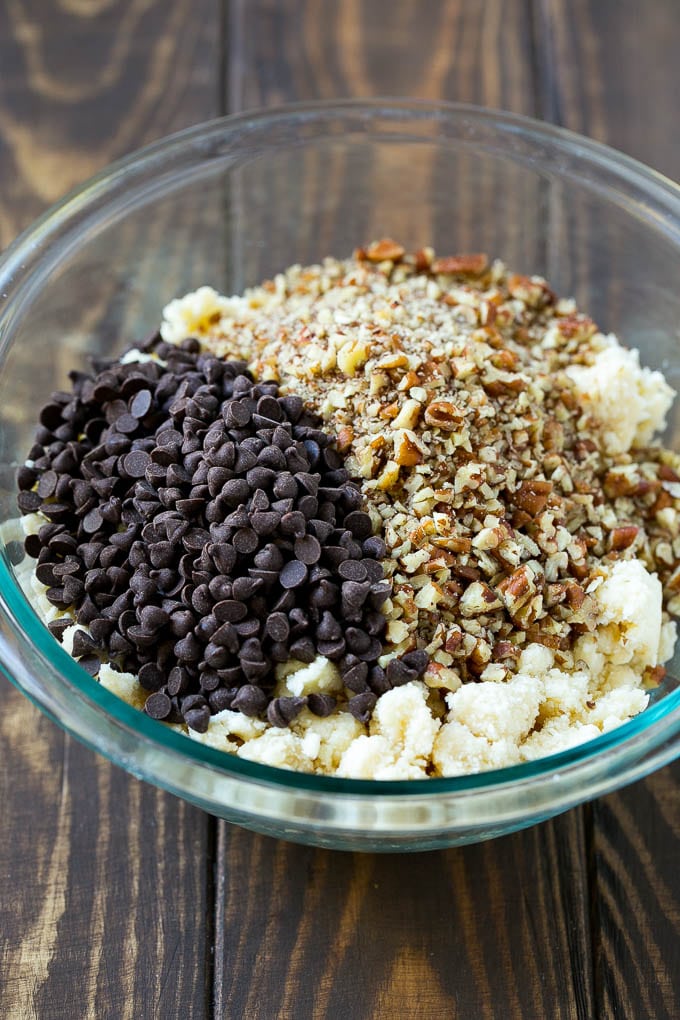 Snowball Cookies Recipe | Mexican Wedding Cookies | Russian Tea Cakes #cookies #pecan #chocolate #baking #dessert #christmas #sadud A bowl of dough topped with miniature chocolate chips and chopped pecans.