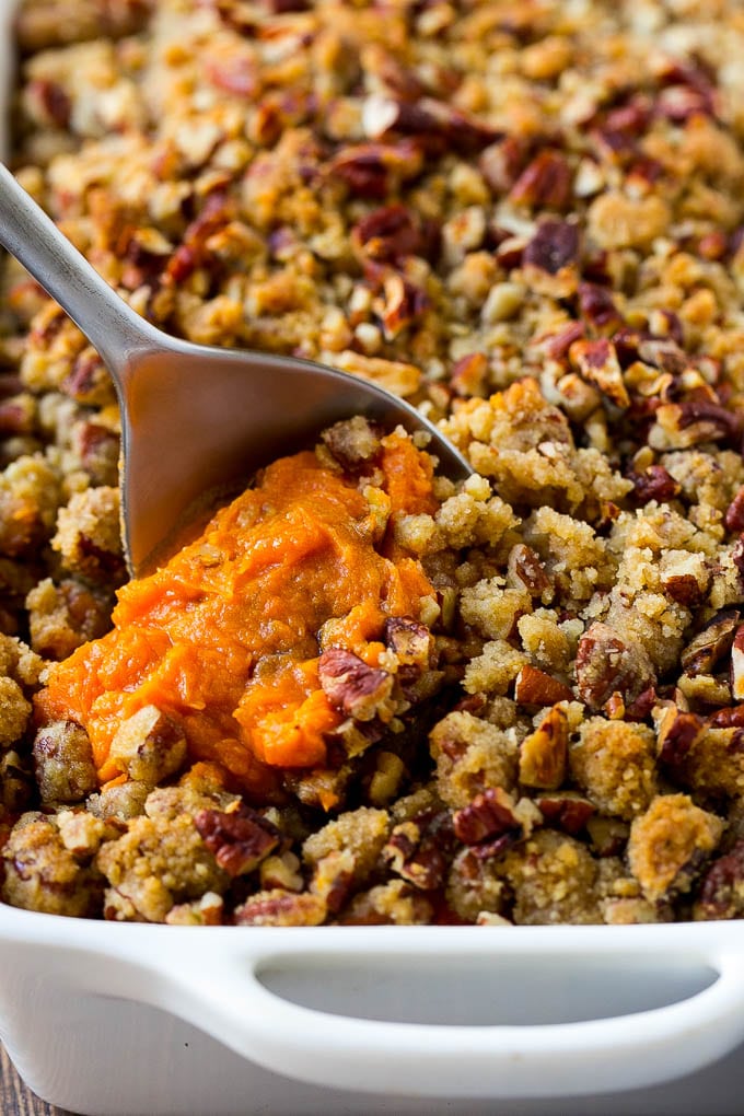 Sweet Potato Casserole with Pecans Recipe | Sweet Potato Casserole | Sweet Potato Side Dish #sweetpotatoes #thanksgiving #pecans #casserole #sidedish #holiday #fall #sadud A dish of sweet potato casserole with pecans with a serving spoon in it.