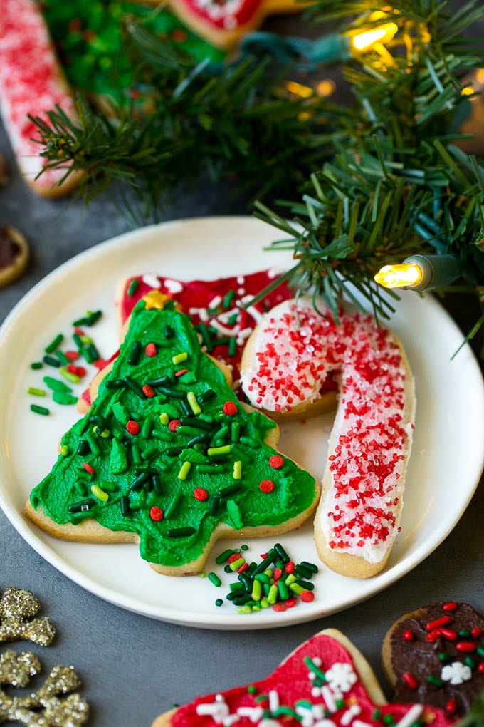 Christmas Sugar Cookies Recipe | Christmas Cookies #cookies #frosting #sprinkles #sugarcookies #christmas #dessert #sadud A selection of Christmas sugar cookies served on a plate, with holiday decorations in the background.
