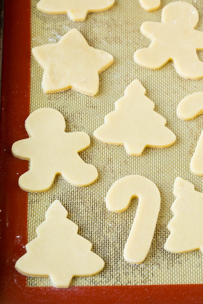 Christmas Sugar Cookies Recipe | Christmas Cookies #cookies #frosting #sprinkles #sugarcookies #christmas #dessert #sadud Cookie dough cut into holiday shapes on a baking sheet.