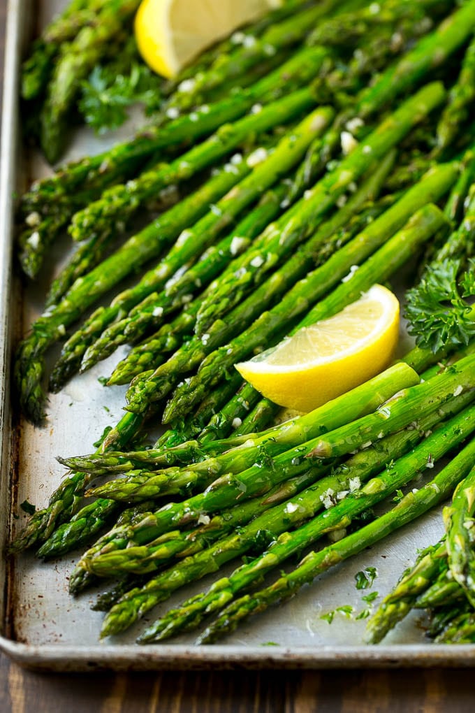 Roasted Asparagus Recipe | Baked Asparagus | Asparagus Side Dish #asparagus #garlic #sidedish #keto #lowcarb #dinner #sadud Roasted asparagus on a sheet pan, topped with chopped parsley and garnished with lemon wedges.
