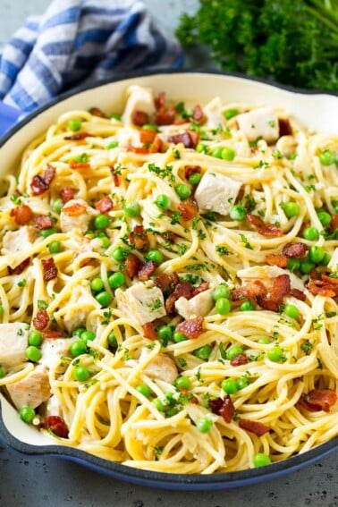 A skillet of turkey pasta carbonara with peas and bacon in a creamy sauce.