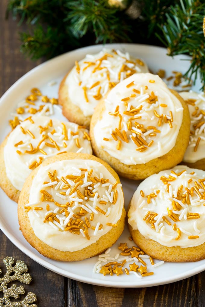 Eggnog Cookies Recipe | Holiday Cookies | Christmas Cookies #cookies #eggnog #baking #christmas #sprinkles #dessert #sadud Eggnog cookies topped with frosting and gold sprinkles on a serving plate.